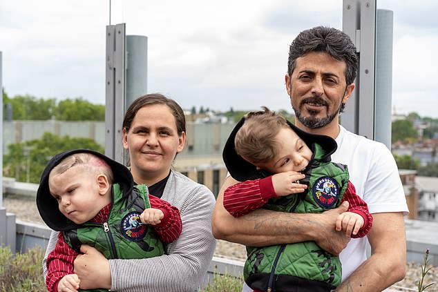 Yigit and Derman's parents stand outside, holding their children.