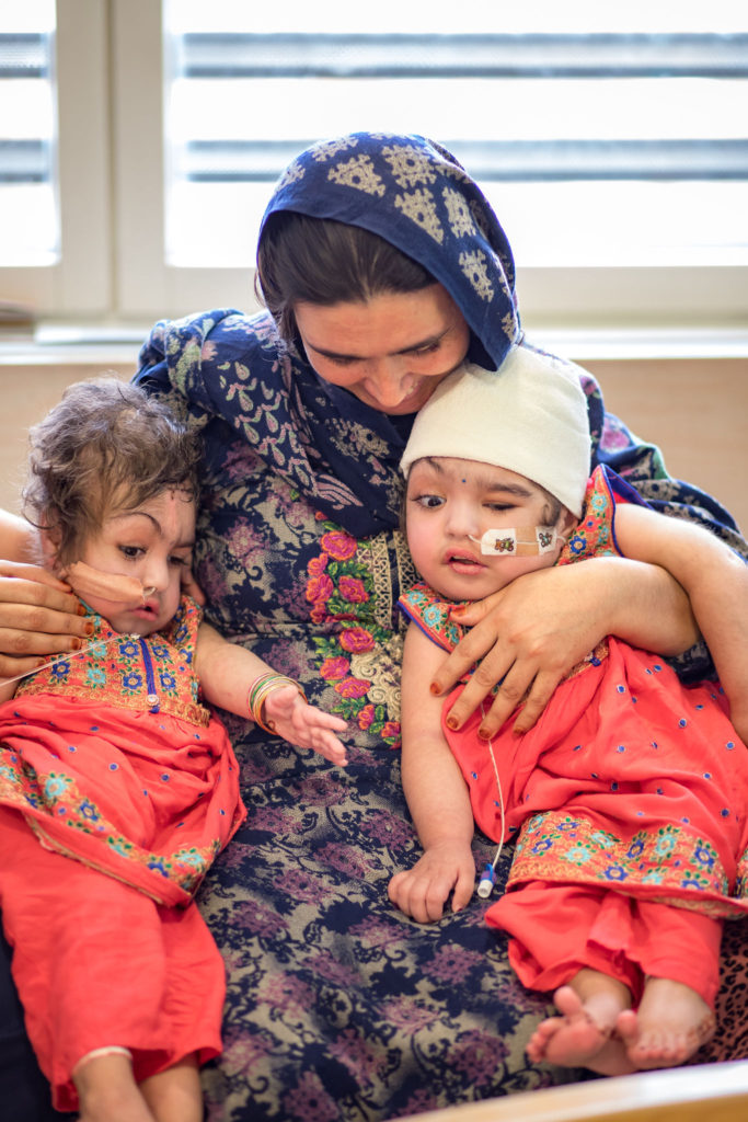 Safa and Marwa's mother holds her children post-operation.